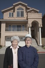 Senior Asian couple in front of house