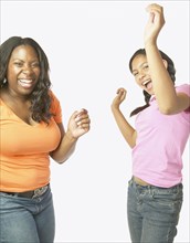 Studio shot of African mother and daughter dancing and laughing
