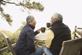 Senior Asian couple drinking coffee outdoors