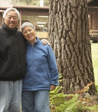 Senior Asian couple hugging and smiling outdoors