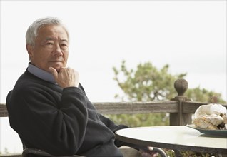Senior Asian man sitting outdoors