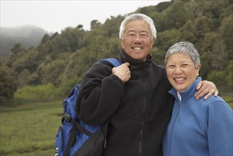 Senior Asian couple with backpack outdoors