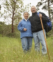 Senior Asian couple with backpack and walking stick outdoors
