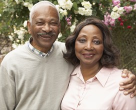 Senior African couple hugging and smiling outdoors