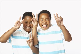 Young African twin brothers smiling and making peace sign