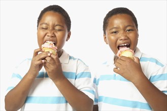 Young African twin brothers eating cupcakes