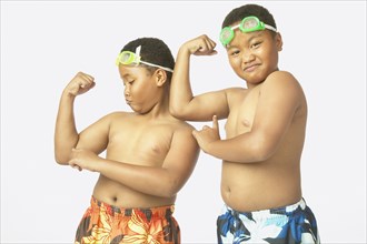 Young African twin brothers in bathing suits flexing