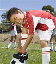 Mixed Race boy tying soccer shoe