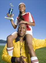 Mixed Race girl on soccer coach's shoulders