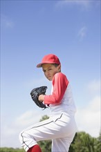 Mixed race boy in baseball uniform pitching in game