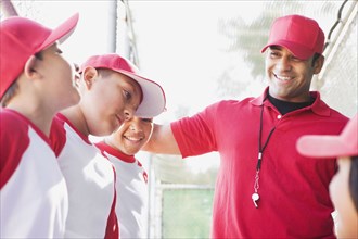 Multi-ethnic boys in baseball uniforms with coach