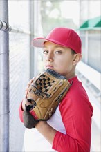 Hispanic boy in baseball uniform holding baseball glove