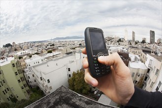 Caucasian man holding cell phone with cityscape in background