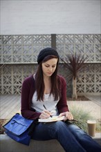 Caucasian woman writing in journal outdoors