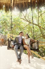Newlywed couple sitting on swing together