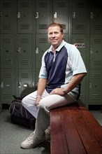 Caucasian man sitting on bench in locker room
