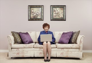 Senior Caucasian woman using laptop on sofa