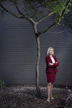 Caucasian businesswoman standing underneath tree