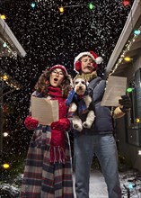Couple singing Christmas carols with dog
