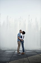 Couple kissing by urban fountain