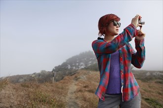 Korean woman taking photograph in remote landscape
