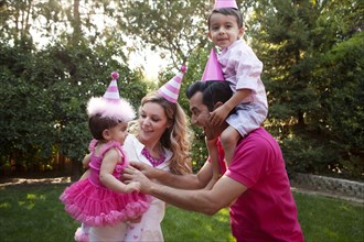 Family wearing party hats together in backyard