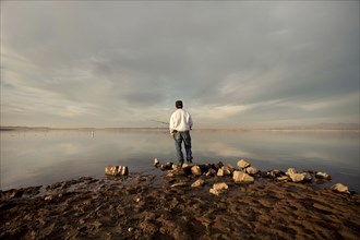 Fisherman at dry lake during drought