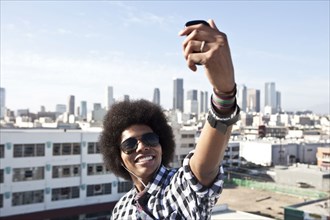 African American man taking cell phone picture from urban rooftop