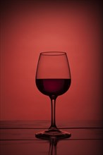 Red wine in wine glass on red background