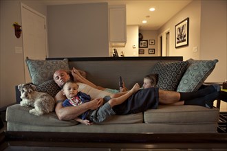 Caucasian father and children relaxing on sofa