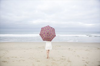 Woman standing with umbrella on beach