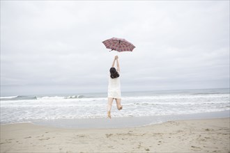 Woman playing with umbrella on beach