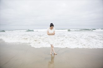 Woman standing near waves on beach