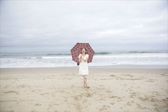 Woman laughing with umbrella on beach