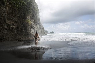 Mixed Race woman standing on rocks on ocean beach
