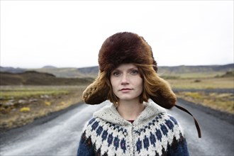 Caucasian woman wearing sweater and fur hat in middle of road