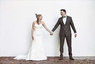 Smiling Caucasian bride and groom holding hands