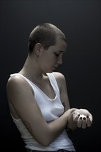 Serious Caucasian woman with shaved-head holding pills