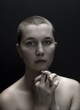 Portrait of serious Caucasian woman with shaved-head and hands clasped
