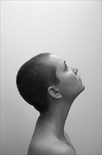 Profile of Caucasian woman with shaved-head looking up