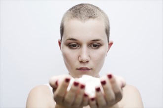 Serious Caucasian woman with shaved-head holding pills