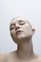 Caucasian woman with shaved-head and eyes closed