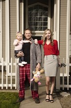 Caucasian couple posing near house with baby daughter