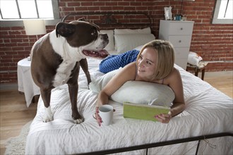 Caucasian woman relaxing with dog on bed