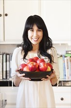 Woman holding bowl of fruit in kitchen