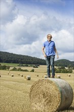 Farmer standing on hay bale in field