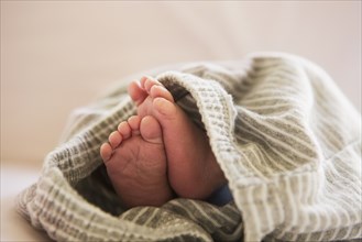 Close up of feet of mixed race baby in blanket
