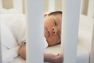 Mixed race baby sleeping in crib