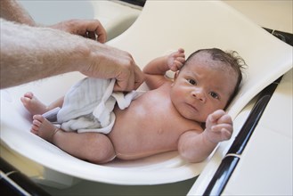 Man bathing mixed race baby