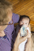 High angle view of father bottle feeding baby